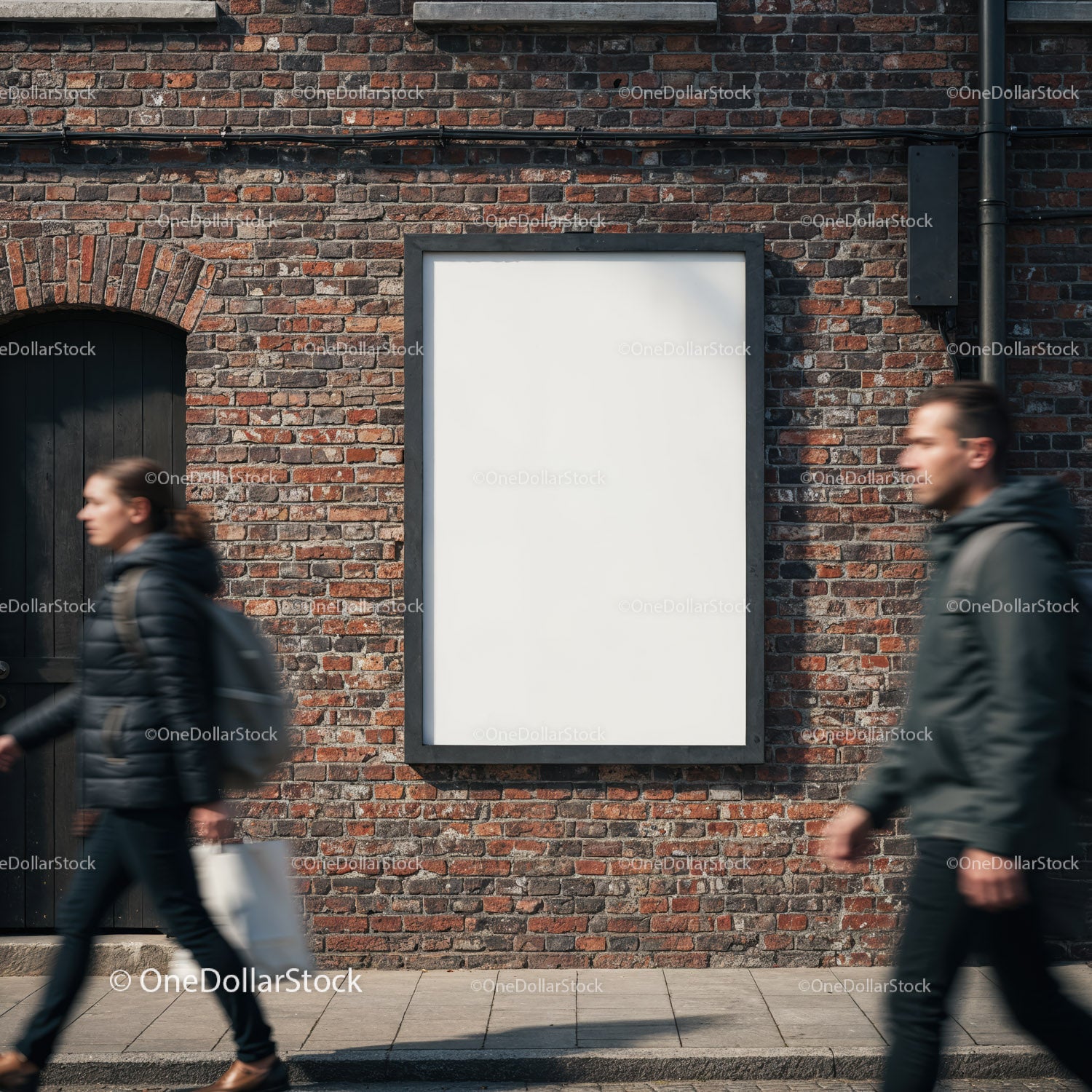 Blank poster on brick wall with pedestrians passing by