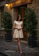 Elegant Woman in Beige Dress Walking on Cobblestone Street in City
