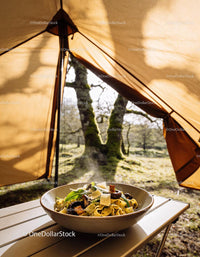 Fresh pasta with mushrooms served in outdoor camping tent