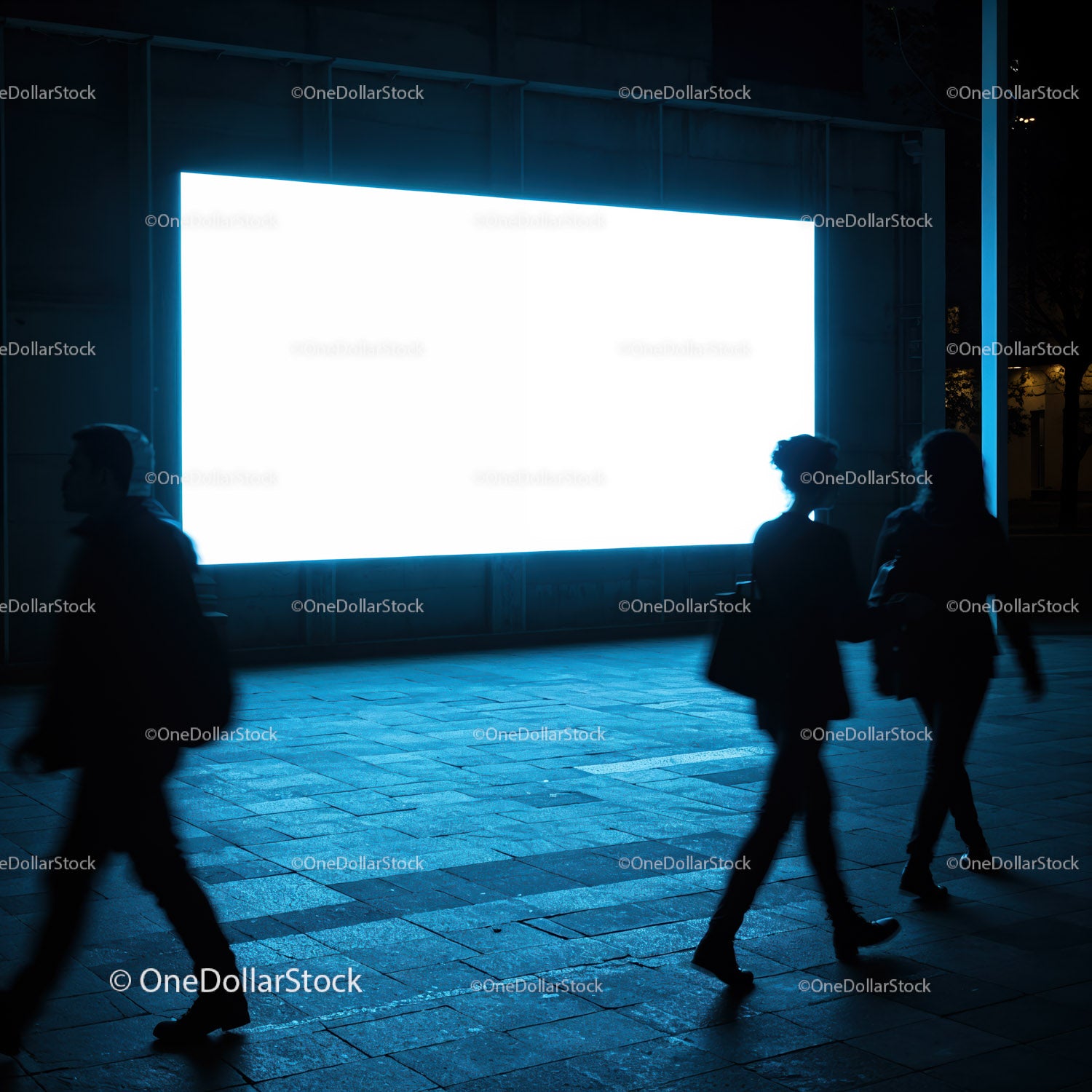 Silhouettes walking past bright city billboard at night