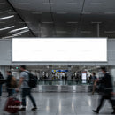Busy airport terminal with blank advertising billboard