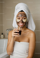 Young Woman Enjoying Facial Mask and Drinking Juice in Bathroom