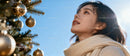 Young woman admiring golden Christmas tree decorations