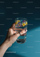 Hand Holding Glass of Water with Floating Edible Flowers