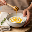 Close-up of Honey Dripping from Wooden Dip in Creamy Yogurt Bowl
