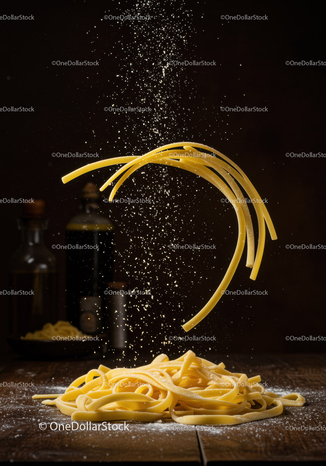 Surowy makaron fettuccine z mąką spadającą na drewnianą powierzchnię