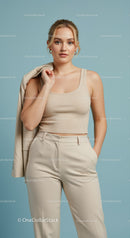 Elegant Woman in Beige Tank Top and Cream Trousers on Light Blue Background