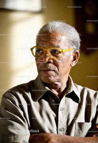Older man with thoughtful expression wearing yellow glasses