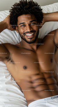 Smiling man relaxing on bed with hands behind head