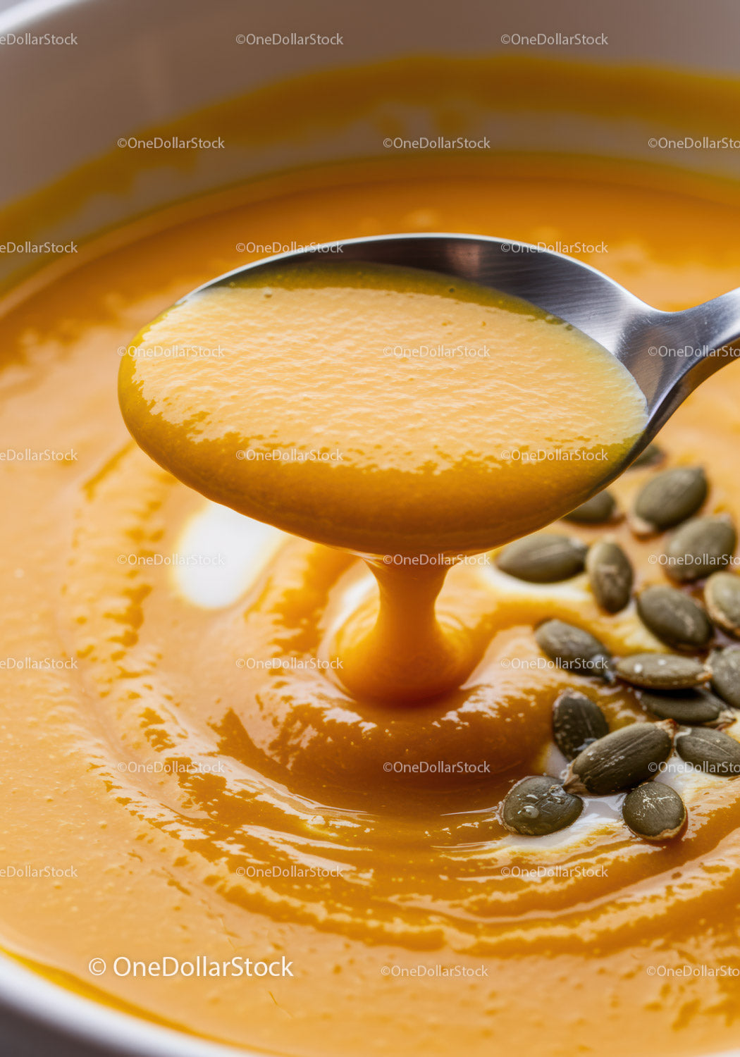 Creamy pumpkin soup with seeds and silver spoon