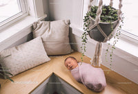 Newborn peacefully sleeping on cozy window bench
