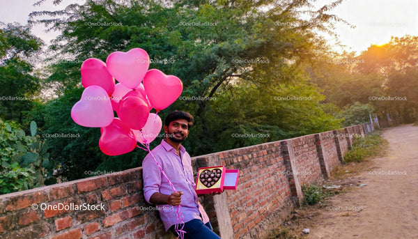 Man Holding Heart-Shaped Balloons and Chocolates Outdoors