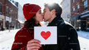 Couple Sharing a Kiss Holding Heart Card Outdoors