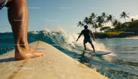 Surfers riding waves near tropical palm coastline