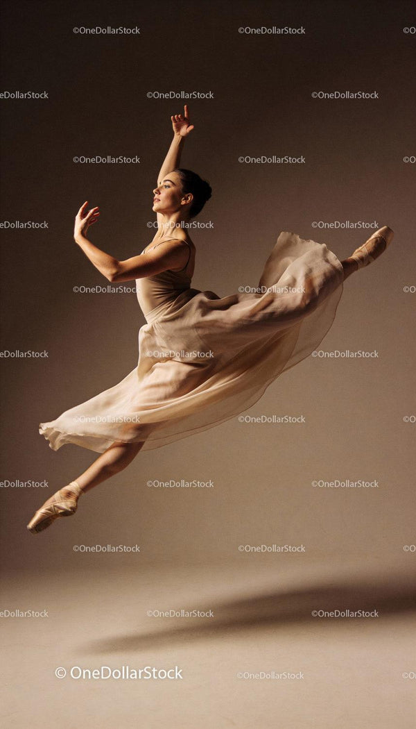 Graceful ballet dancer leaping in soft studio light