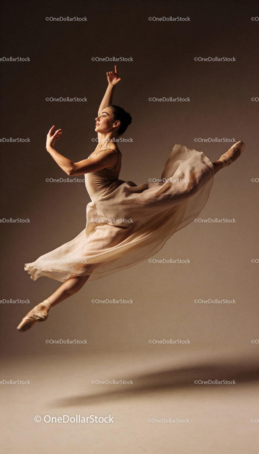 Graceful ballet dancer leaping in soft studio light