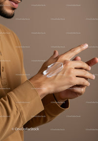 Close-up of a man applying moisturizer on hand for skincare routine
