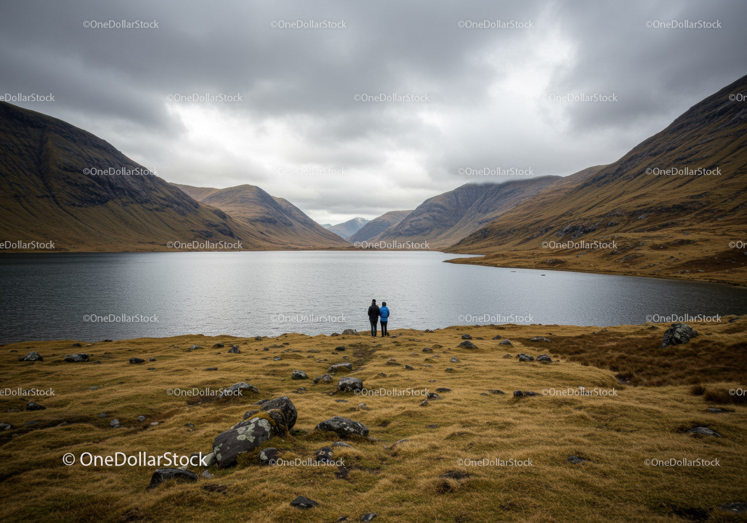 Majestic Mountain Lake Scene with Overcast Skies and Two Hikers