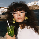 Stylish Woman with Glasses Holding Green Smoothie Near Seaside