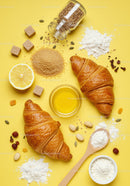 Fresh croissants with baking ingredients on yellow background