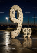 Large illuminated number nine sculpture near harbor at dusk