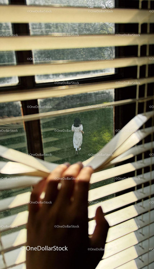 Person watching woman walking outside through blinds
