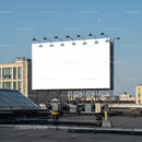 Large blank billboard on city rooftop under clear sky
