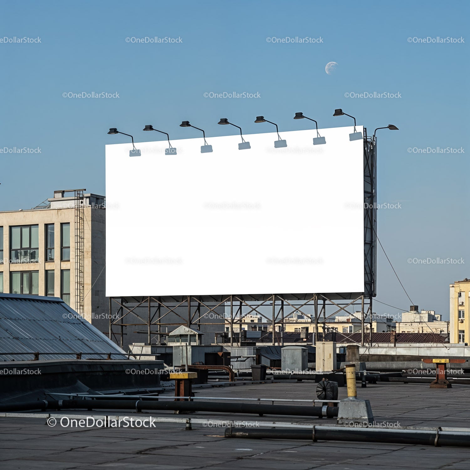 Large blank billboard on city rooftop under clear sky