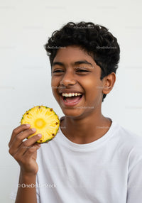 Young Boy Laughing and Holding a Pineapple in a Bright Studio Setting