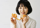 Portrait of a Smiling Woman Holding Fresh Mandarins with Bright Colors