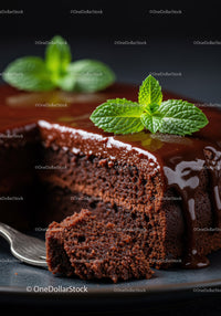 Rich chocolate cake slice with glossy ganache and mint
