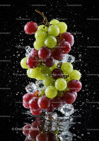 Fresh green and red grapes splashing with ice cubes