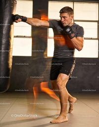 Focused athlete training with boxing bag indoors