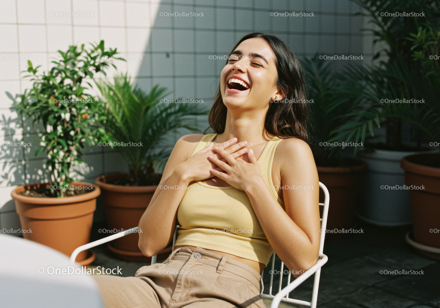 Joyful Woman Sitting Outdoors Surrounded by Green Potted Plants