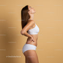 Fit Woman in White Sportswear Posing with Confidence Against Beige Background