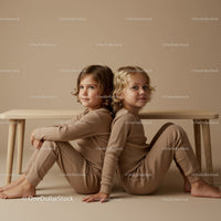 Two children sitting back to back under wooden bench