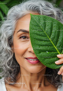 Smiling Elderly Woman with Green Leaf Covered Face in Nature