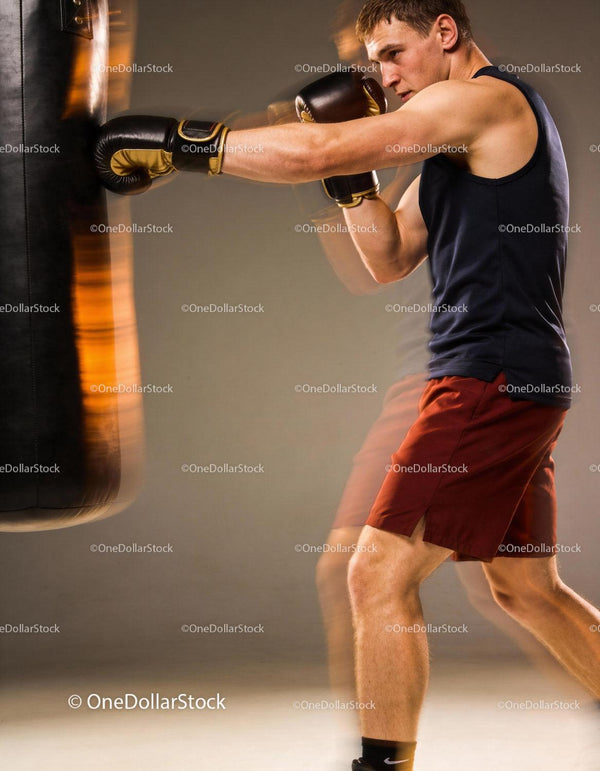 Focused boxer training with powerful punch on bag