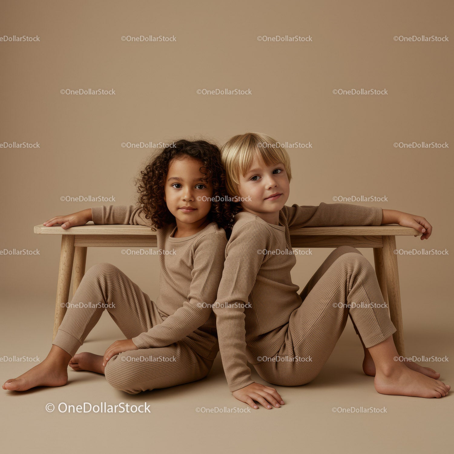 Two children sitting back to back near wooden bench
