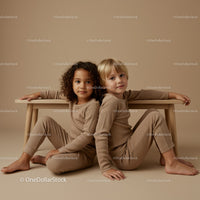 Two children sitting back to back near wooden bench