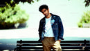 Casual young man posing by park bench outdoors