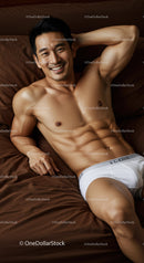 Smiling young man relaxing on bed in white underwear