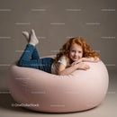 Smiling redhead girl relaxing on soft pink bean bag