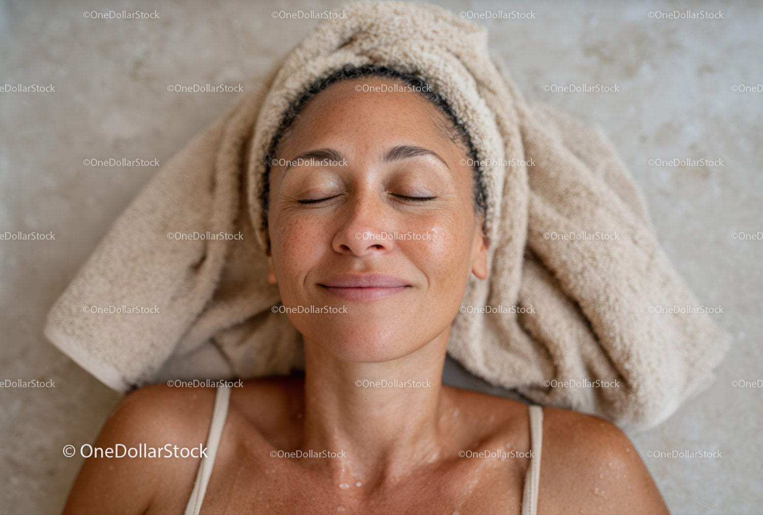 Relaksująca się kobieta z ręcznikiem leżąca na podłodze spa i ciesząca się dobrym samopoczuciem