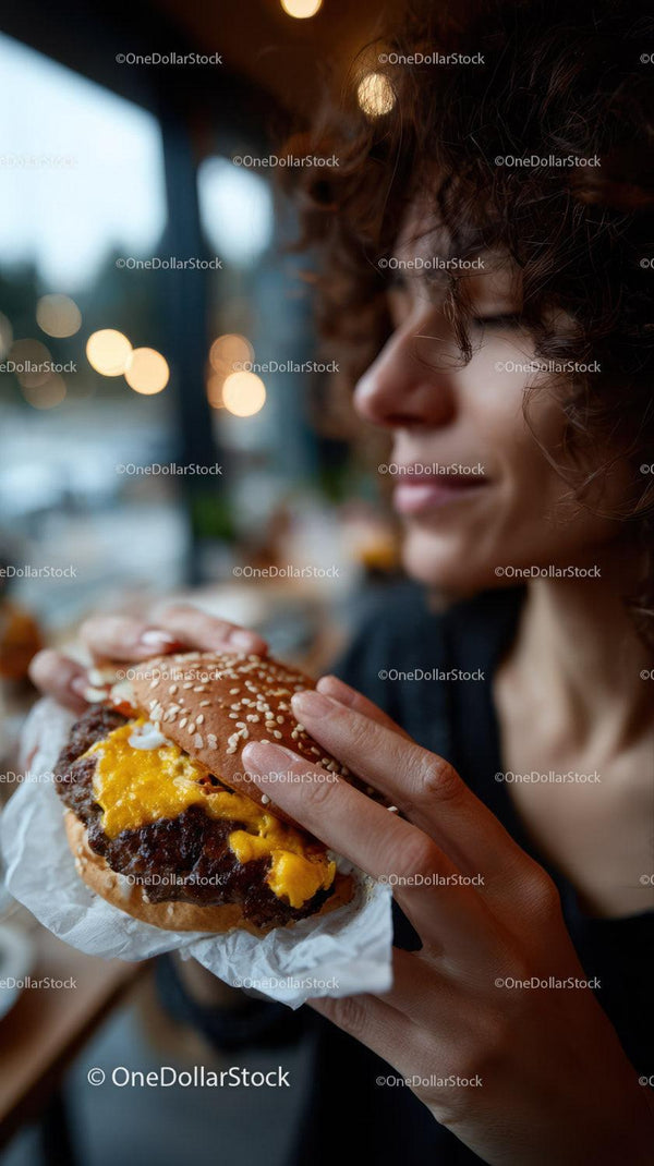 Close-up of Woman Enjoying Delicious Cheeseburger in Cozy Café Atmosphere