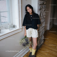 Casual Young Woman with Wildflowers Indoors Standing by the Window