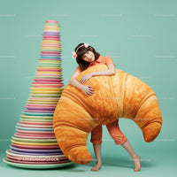 Young woman hugging giant croissant with colorful plates