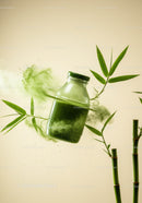 Glass jar with green powder surrounded by bamboo leaves