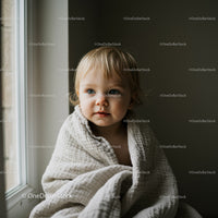 Toddler wrapped in cozy blanket by the window
