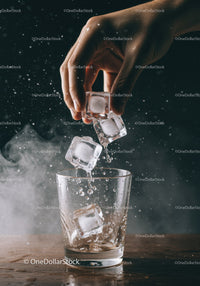 Hand Dropping Ice Cubes Into Clear Glass With Splash